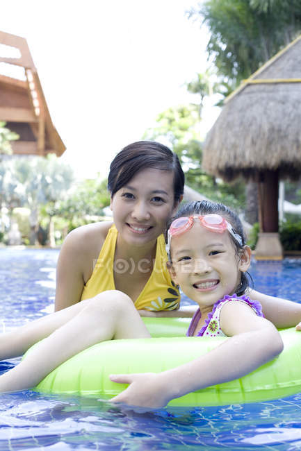 Cinese madre e figlia avendo divertimento e guardando in macchina fotografica in piscina — Foto stock