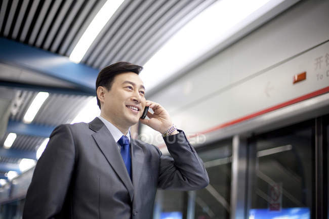 Chinese businessman talking on phone at subway station — Stock Photo