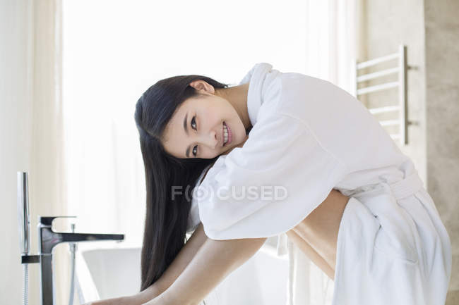 Mujer china sentada en el baño en albornoz - foto de stock
