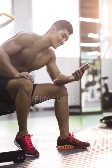 Homem chinês usando smartphone no ginásio — Fotografia de Stock