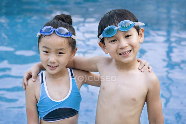 Chinesischer Junge und Mädchen in Schwimmbrille umarmen sich am Pool — Stockfoto