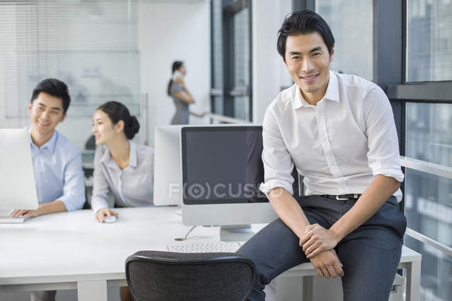 Portrait of Chinese businessman in office with colleagues in background — Stock Photo