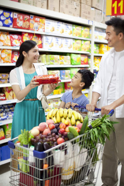 Pais chineses com filho fazendo compras no supermercado — Fotografia de Stock