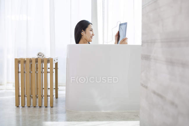Китайська жінка, що використовує цифровий планшетний у ванній — стокове фото