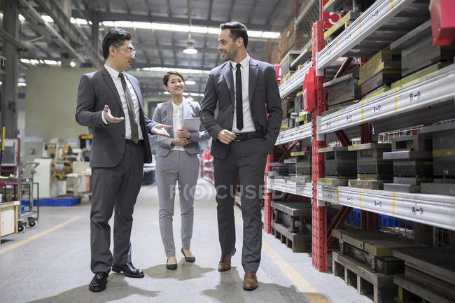 Gente de negocios hablando mientras inspeccionan la fábrica industrial - foto de stock