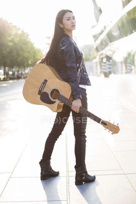 Китайская гитаристка, стоящая на улице с гитарой — стоковое фото