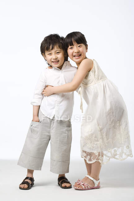 Азиатские братья и сестры обнимаются на белом фоне — стоковое фото