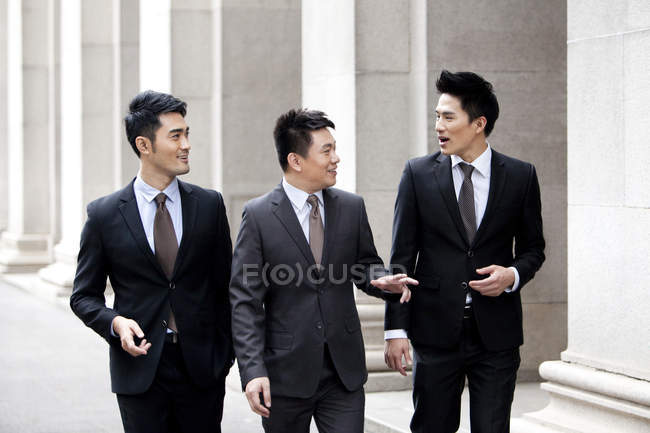 Chinese business team walking and talking on street — Stock Photo