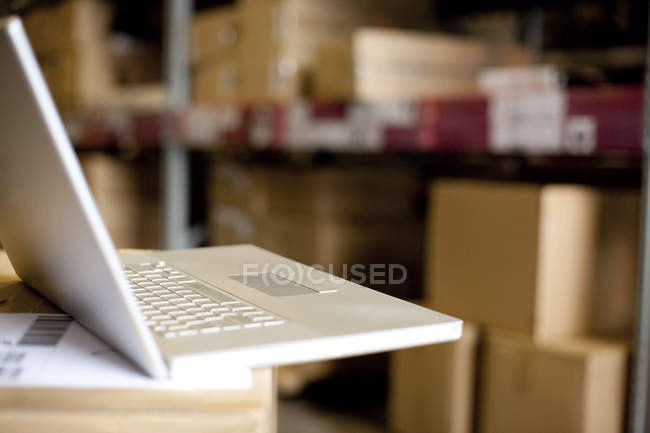 Laptop on cardboard box in warehouse — Stock Photo
