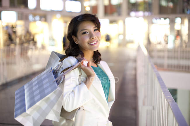 Mulher chinesa com sacos de compras em pé na rua — Fotografia de Stock