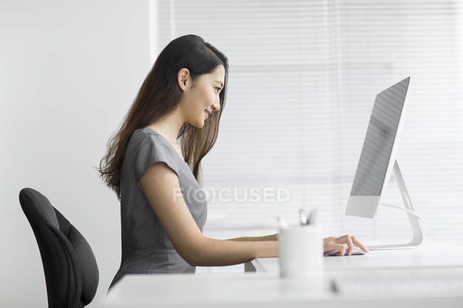 Вид сбоку на предпринимательницу, использующую компьютер в офисе — стоковое фото