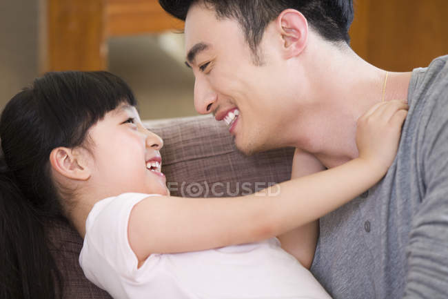 Китайский отец играет с дочерью на диване — стоковое фото