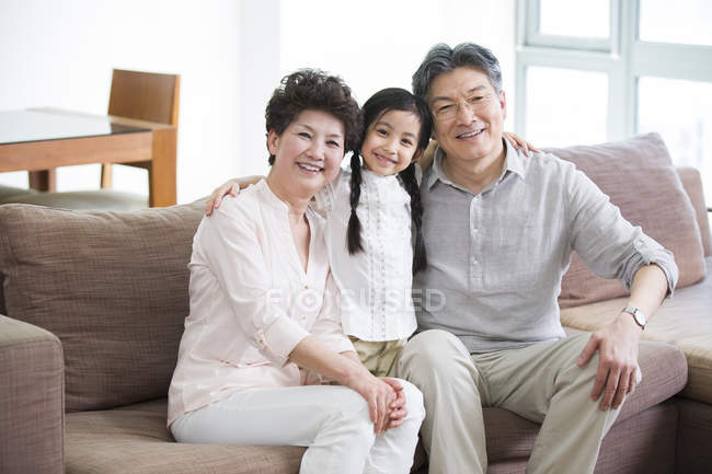 Китаянка с бабушкой и дедушкой на диване в гостиной — стоковое фото