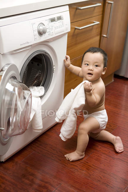 Bebê chinês colocando roupa fora da máquina de lavar roupa — Fotografia de Stock