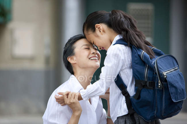 Chinese schoolgirl standing face to face with grandmother — Stock Photo