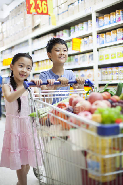 Niños chinos comprando frutas y verduras en el supermercado - foto de stock