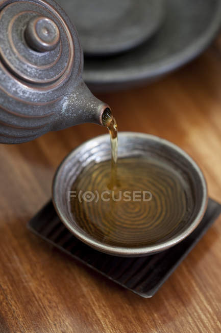 Крупный план травяного чая, наливающегося в чашку — стоковое фото