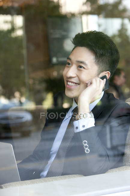 Китайский бизнесмен разговаривает по телефону в кафе — стоковое фото