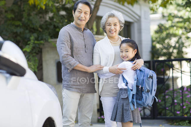 Chinese grandparents with schoolgirl posing at street — Stock Photo