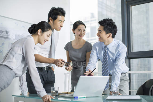 Equipo de negocios chino hablando en reunión con el ordenador portátil - foto de stock