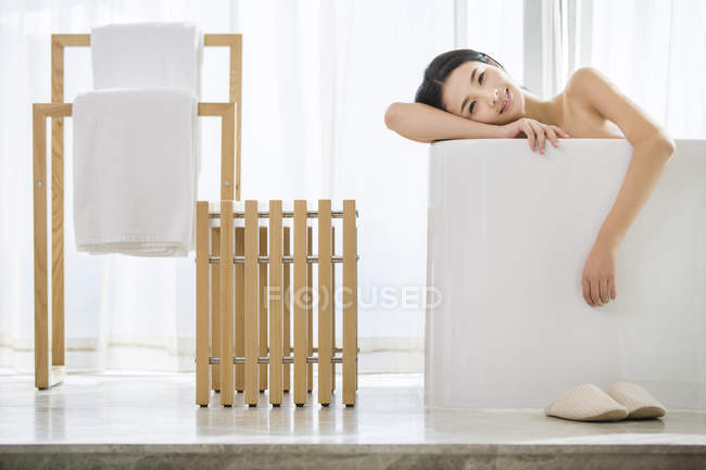 Chinese woman relaxing in bathtub and looking in camera — Stock Photo