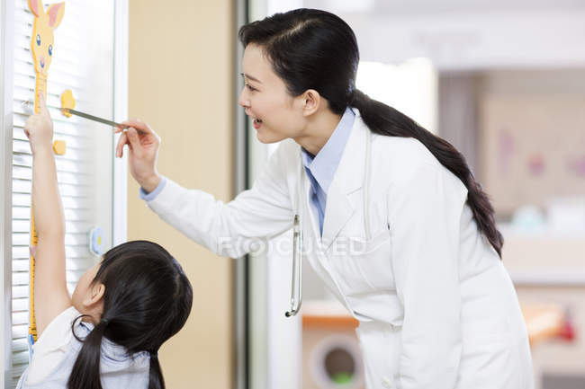 Médecin chinois mesurant la hauteur fille — Photo de stock