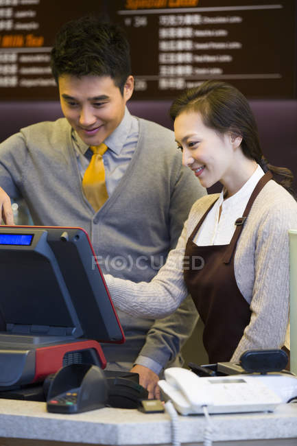Chinese coffee store shopkeeper and waitress using cash register — Stock Photo
