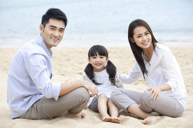 Familia china descansando en la playa de arena - foto de stock
