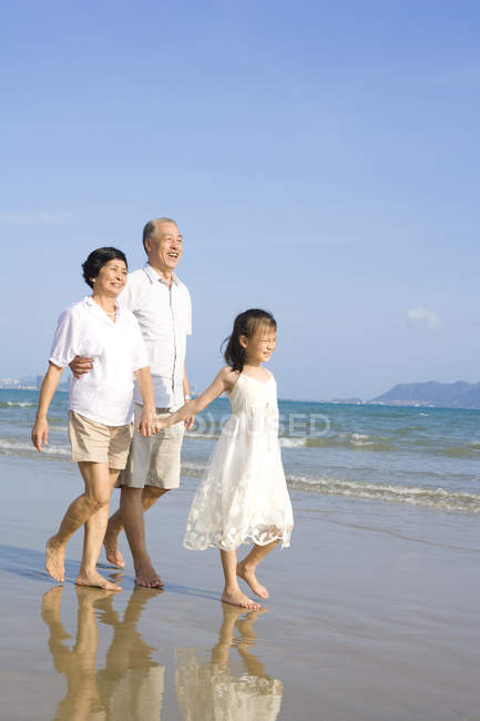 Avós chineses e neta andando ao longo da praia — Fotografia de Stock