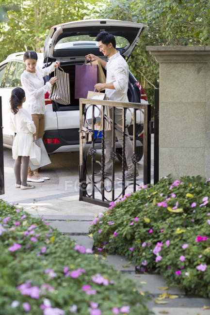 Família chinesa tirando sacos de compras do porta-malas do carro — Fotografia de Stock