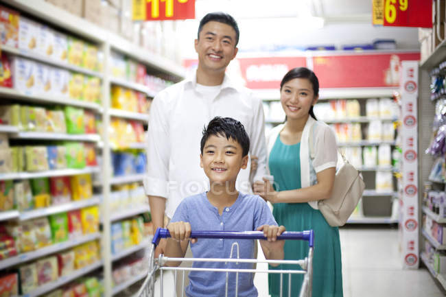 Pais chineses com filho fazendo compras no supermercado — Fotografia de Stock