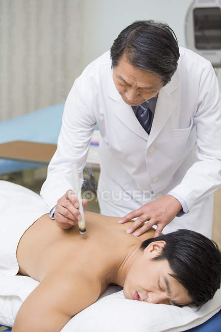 Médico chino senior que da terapia de moxibustión - foto de stock