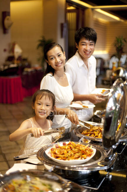 Chinese parents with daughter taking food at buffet — Stock Photo