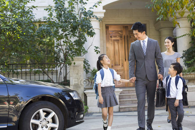 Chinese couple walking with school children at street — Stock Photo