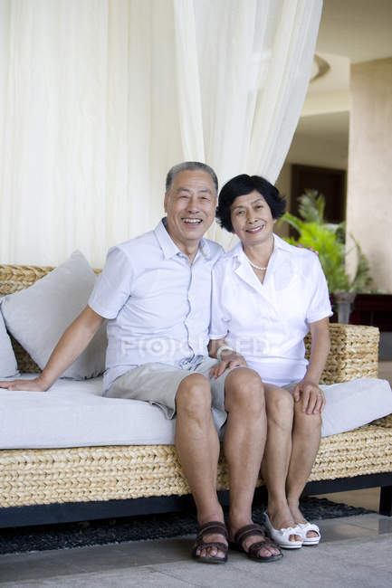 Senior Cinese coppia seduta sul divano al resort e guardando in macchina fotografica — Foto stock