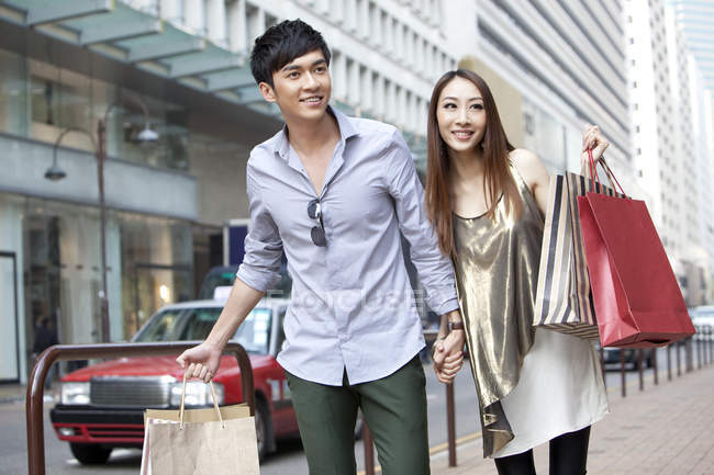 Китайская пара с пакетами для покупок ходит по улице — стоковое фото