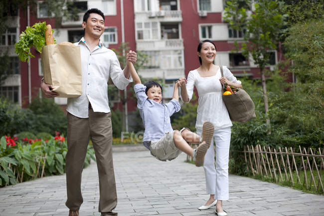 Famille chinoise avec fils balançant marchant dans la rue avec des épiceries — Photo de stock