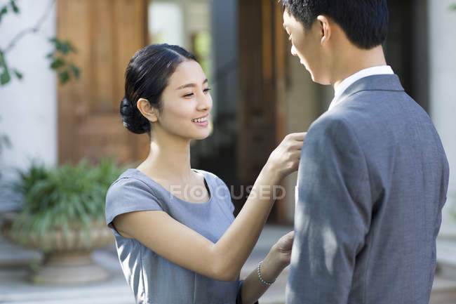 Jeune femme chinoise ajuster cravate homme sur la rue — Photo de stock