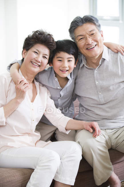 Бабушка с дедушкой и внук сидят на диване — стоковое фото