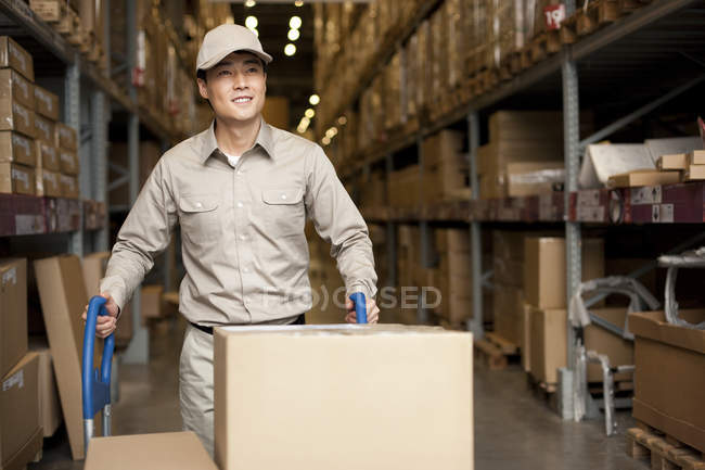 Masculino chinês armazém trabalhador empurrando caixas — Fotografia de Stock