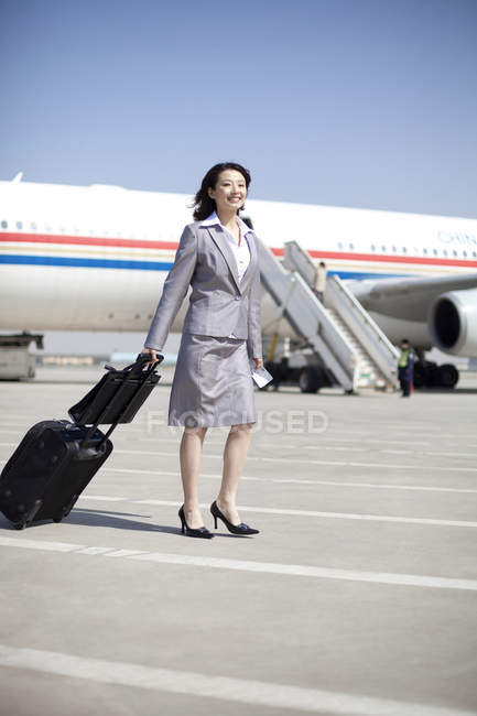 Chinese businesswoman pulling luggage on airplane runway — Stock Photo