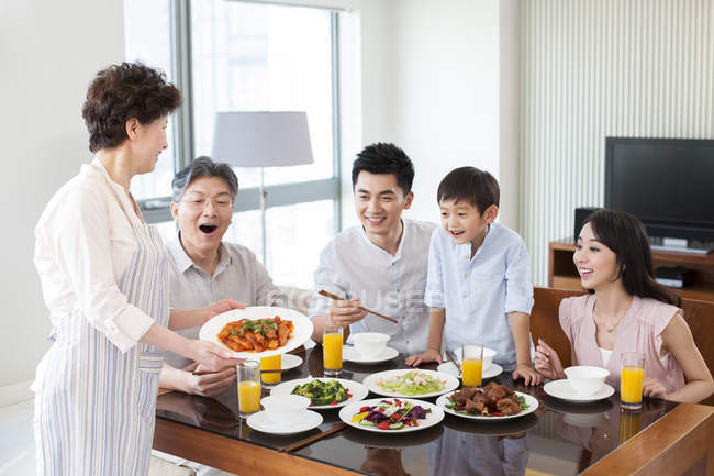 Abuela china sirviendo la cena para la familia feliz - foto de stock