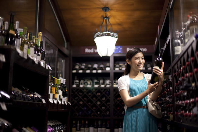 Chinese woman choosing wine in cellar — Stock Photo