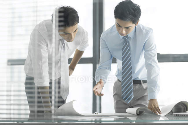 Chinesische Geschäftsleute diskutieren Bauplan am Schreibtisch im Büro — Stockfoto