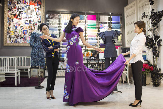 Créateurs de mode chinois examinant robe sur le client — Photo de stock