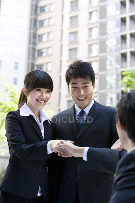 Los empresarios chinos estrechando la mano con el hombre en la calle - foto de stock