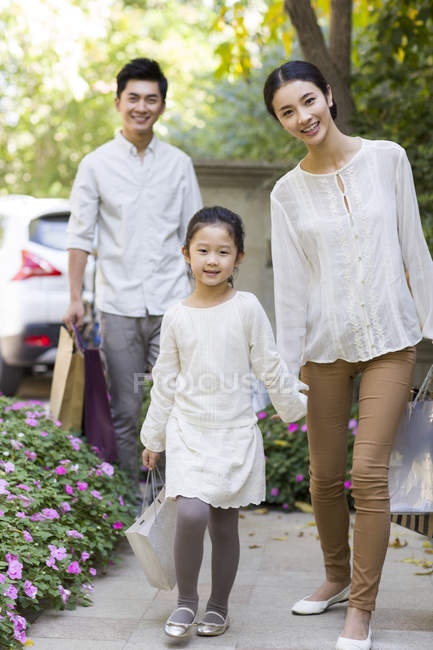 Los padres chinos y su hija regresan de las compras - foto de stock