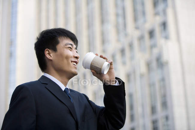 Chinese businessman drinking coffee on street — Stock Photo