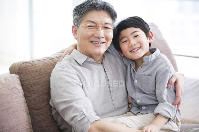 Chinese grandson sitting on grandfather lap — Stock Photo