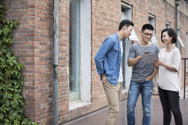 Chinese casual business team talking with digital tablet in city — Stock Photo